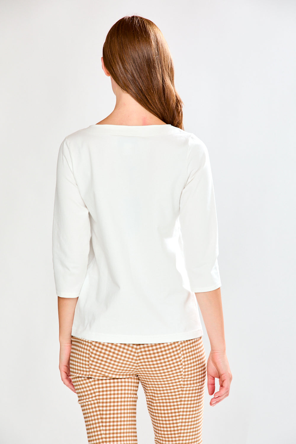 Woman wearing a white top and checkered pants on a plain background