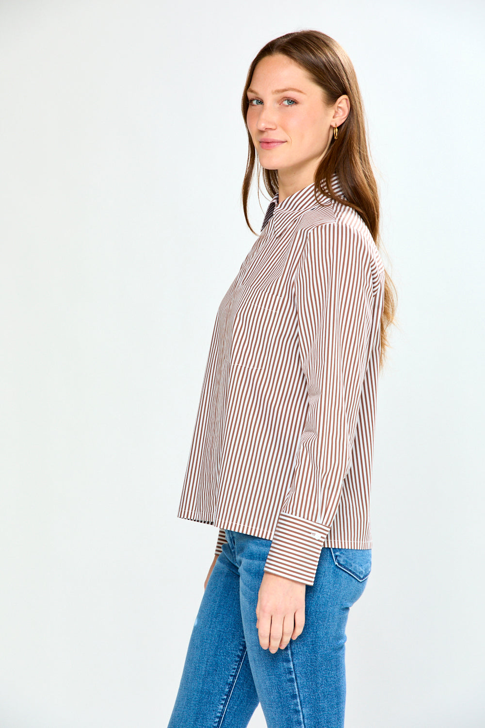 Woman wearing a striped shirt and jeans on a white background