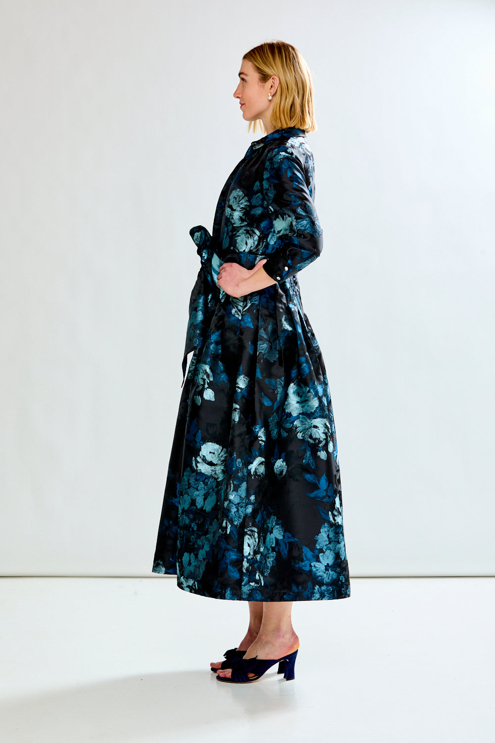 Woman wearing a long floral dress against a white background