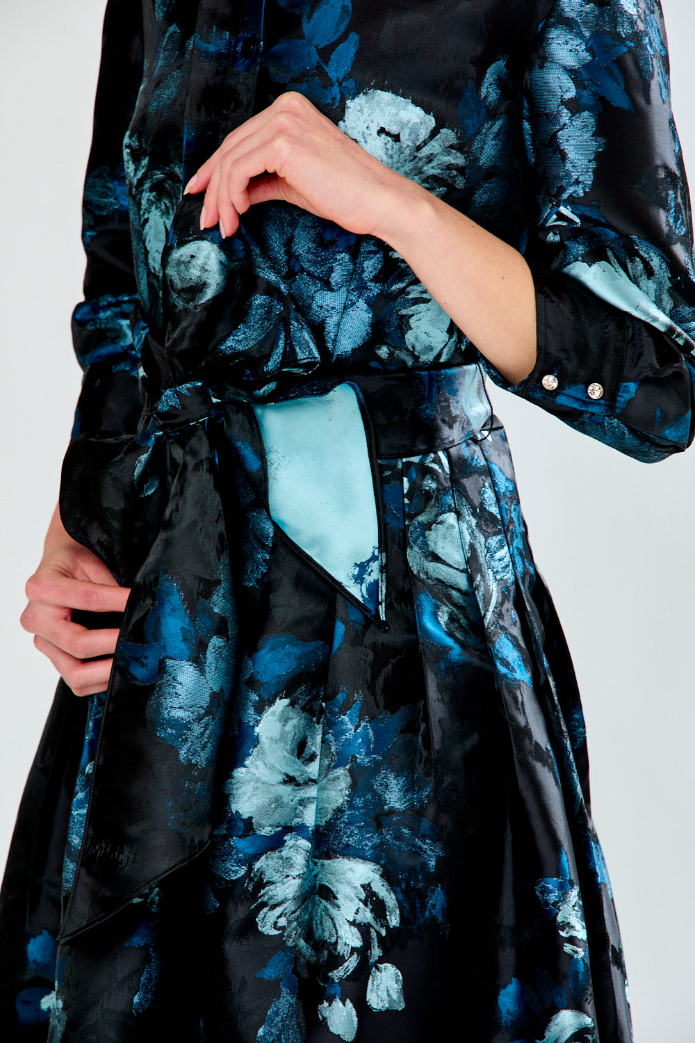 Black floral-patterned dress with a light blue belt on a white background