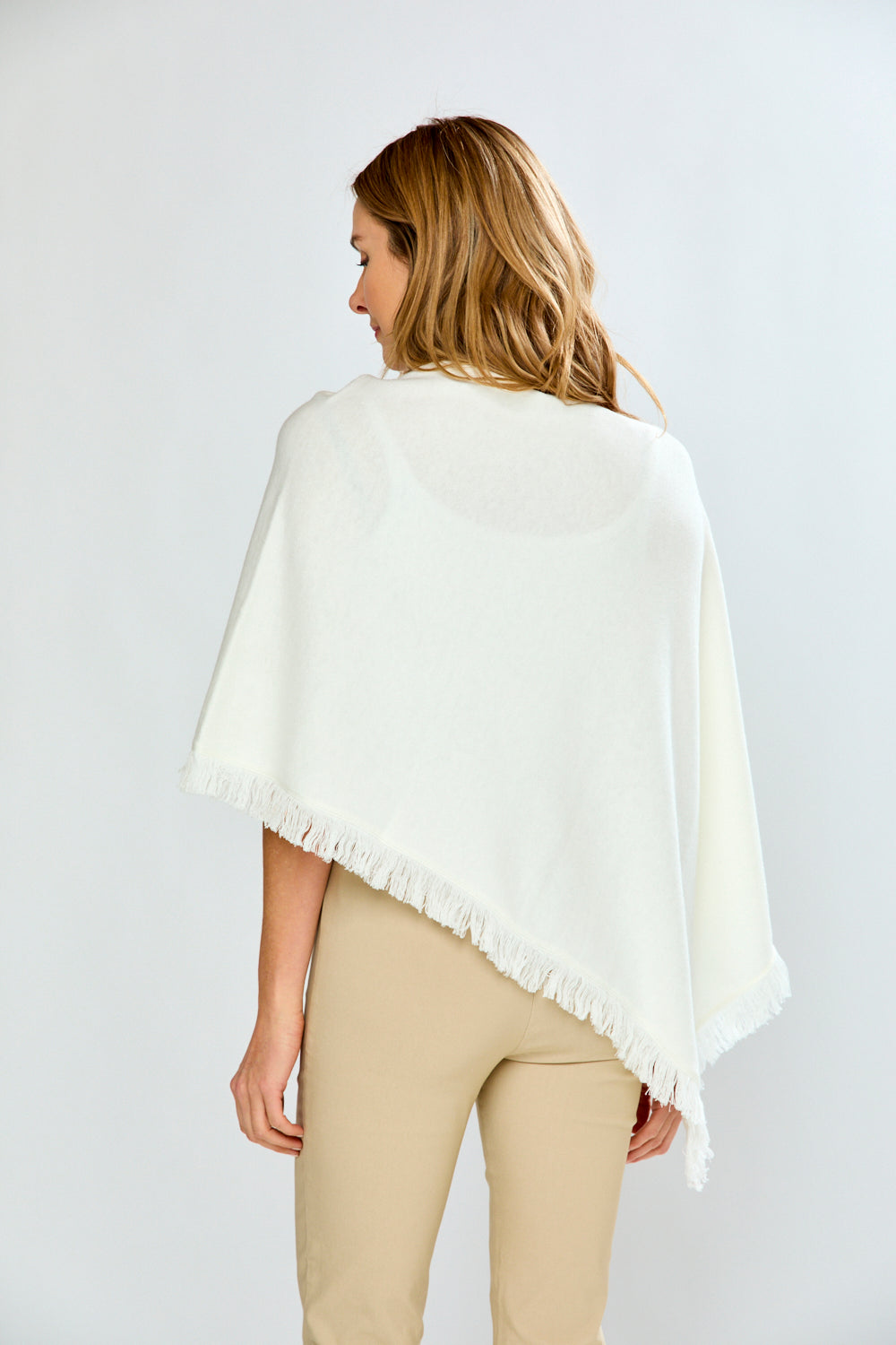 Woman wearing a white poncho against a plain background