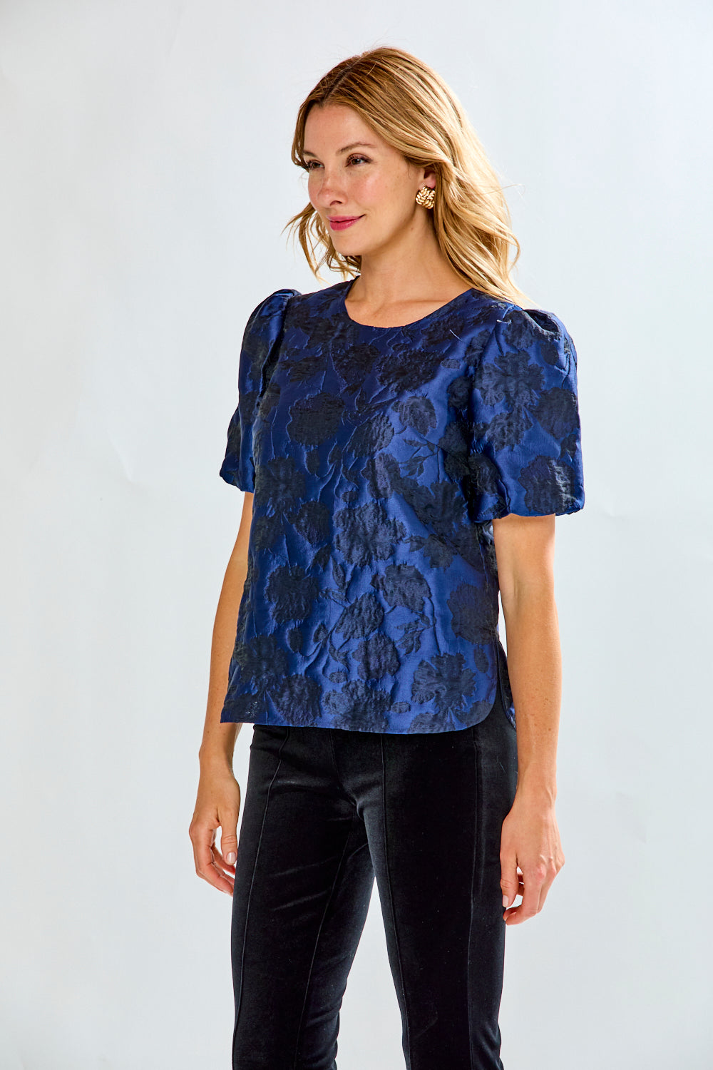 Woman wearing a blue floral blouse with puff sleeves against a white background