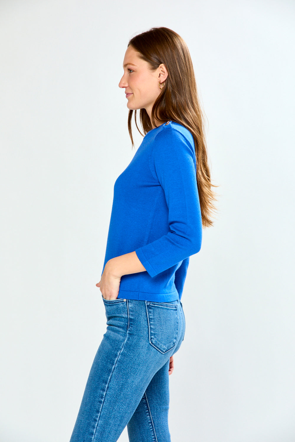 Woman wearing a blue sweater and jeans on a white background