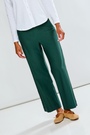 Person wearing green pants and a white top on a light background