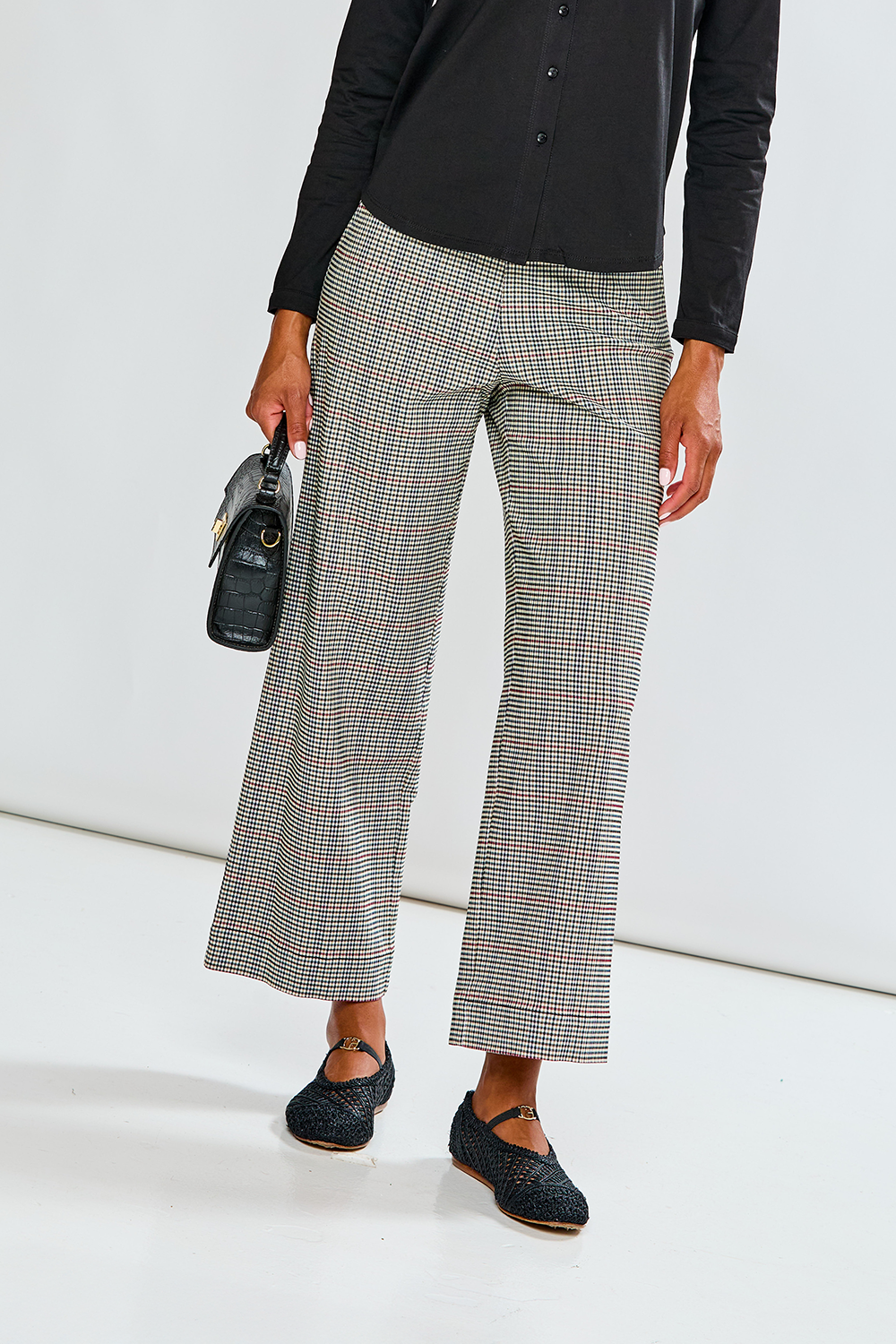 Person wearing checkered pants and black shoes on a white background