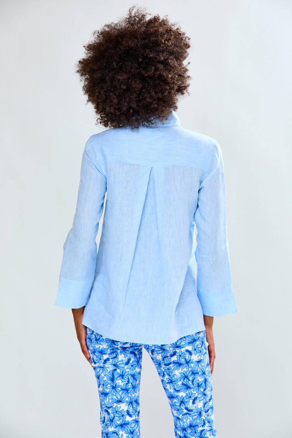 Person wearing a light blue shirt and patterned pants on a white background