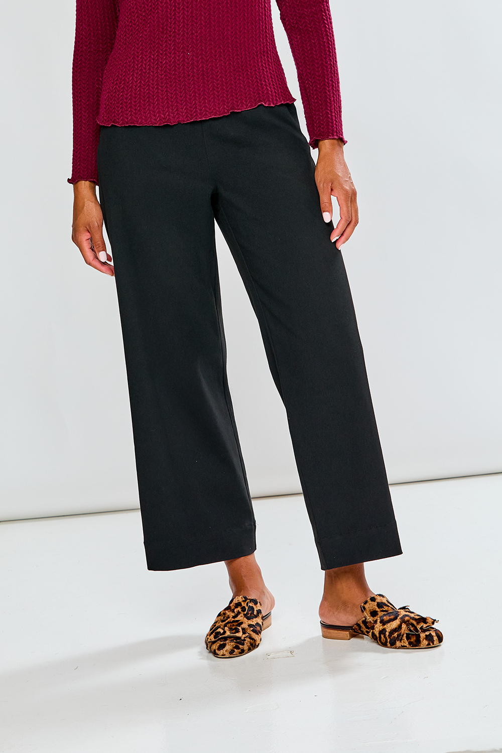 Person wearing black pants and leopard print shoes on a white background