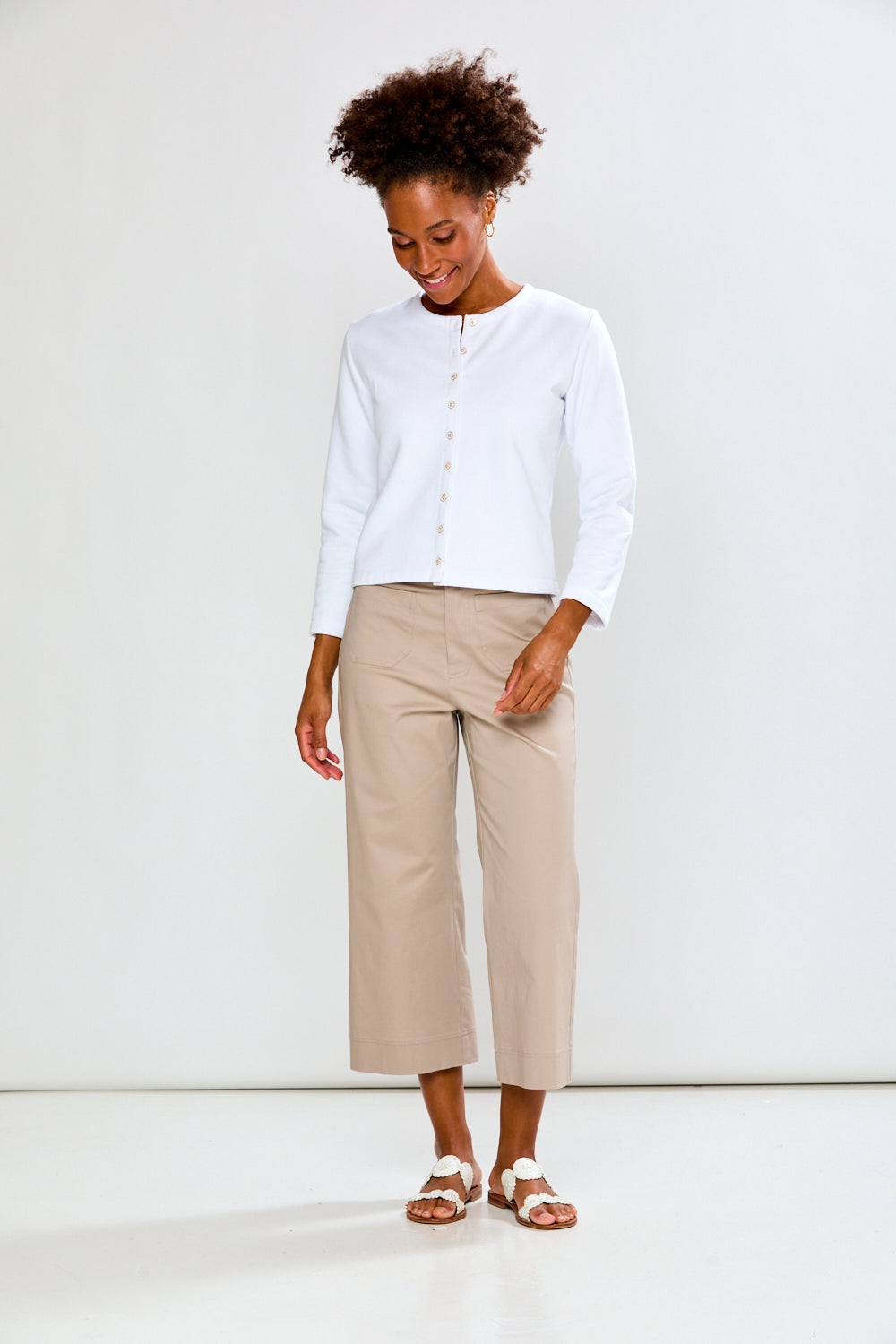 Woman wearing a white blouse and beige pants on a white background