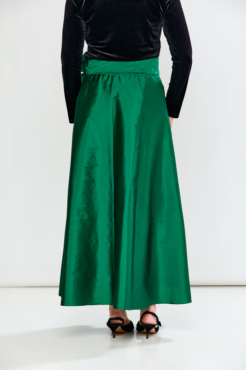 Woman wearing a Black top and Emerald skirt on a white background