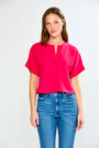 Woman wearing a bright pink top and blue jeans on a white background