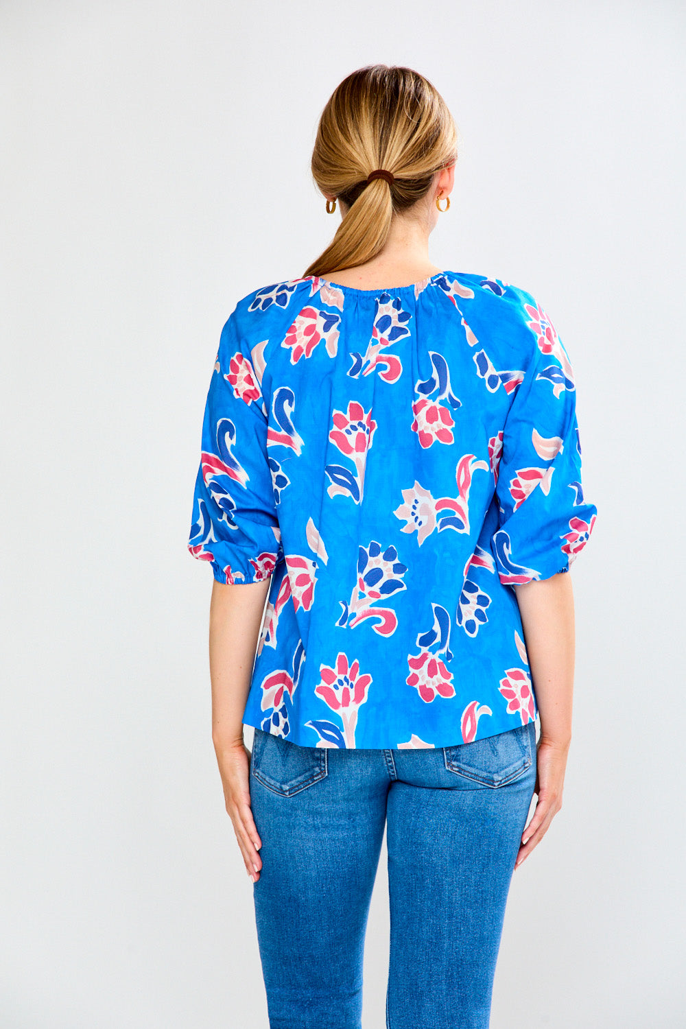 Woman wearing a blue floral blouse against a white background