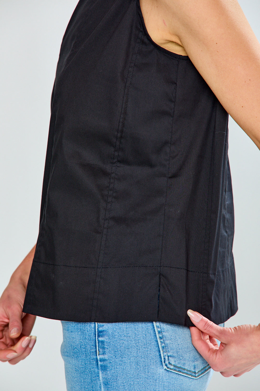 Black sleeveless top worn by a person on a plain background