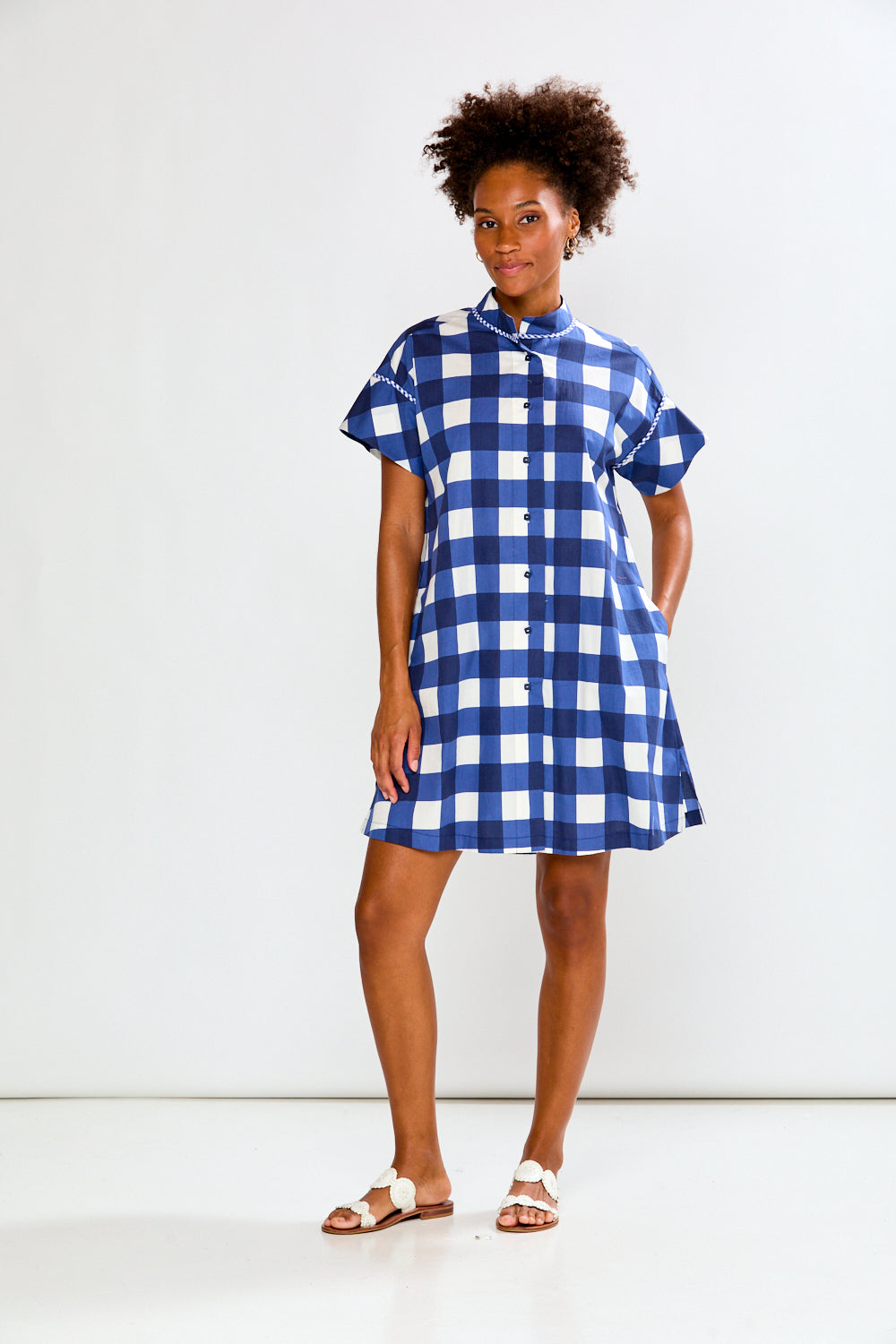 Woman wearing a blue and white checkered dress against a white background