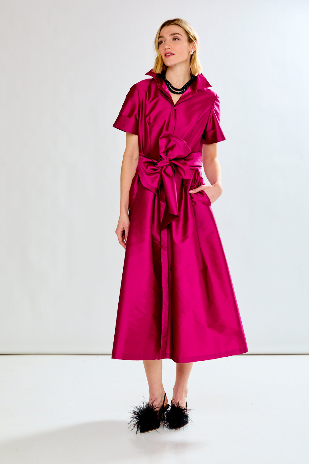 Woman wearing a bright pink dress with a white background