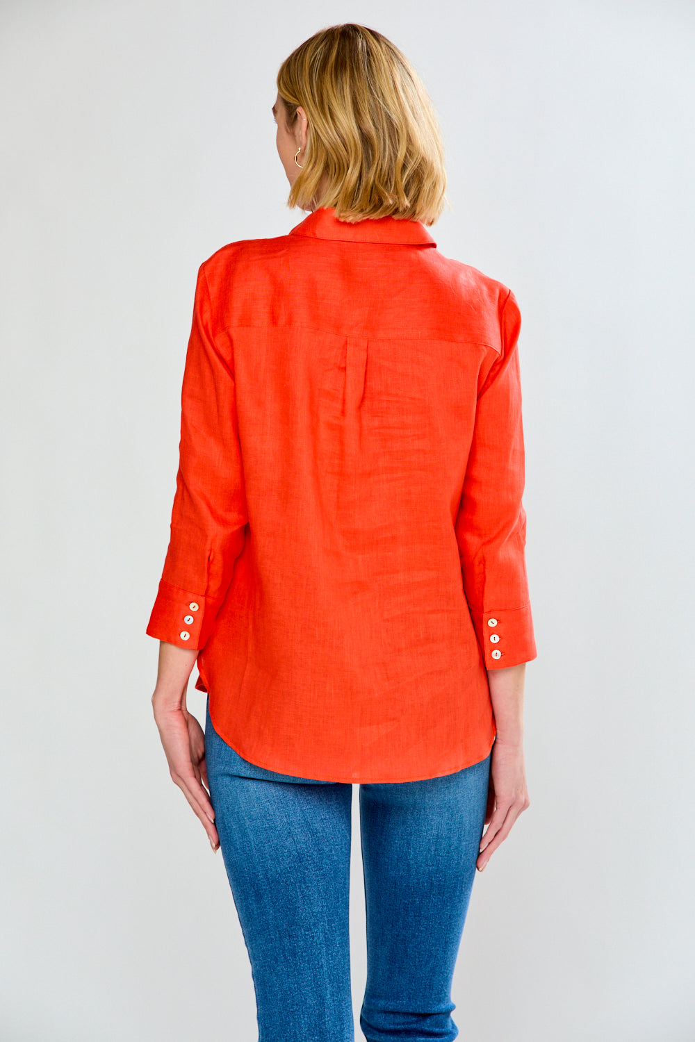 Person wearing an orange shirt and blue jeans on a white background