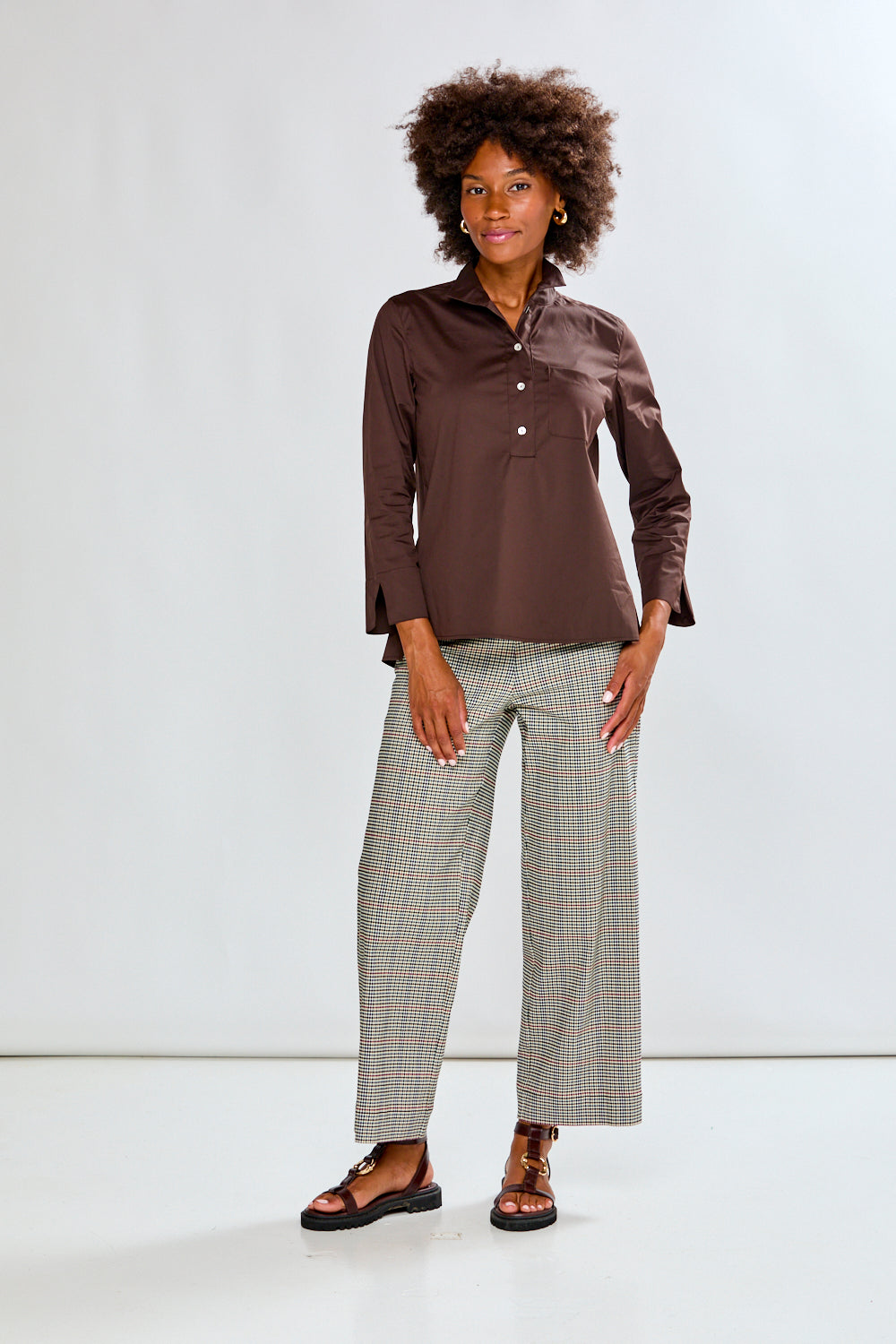 Woman wearing a chocolate shirt and plaid pants on a white background