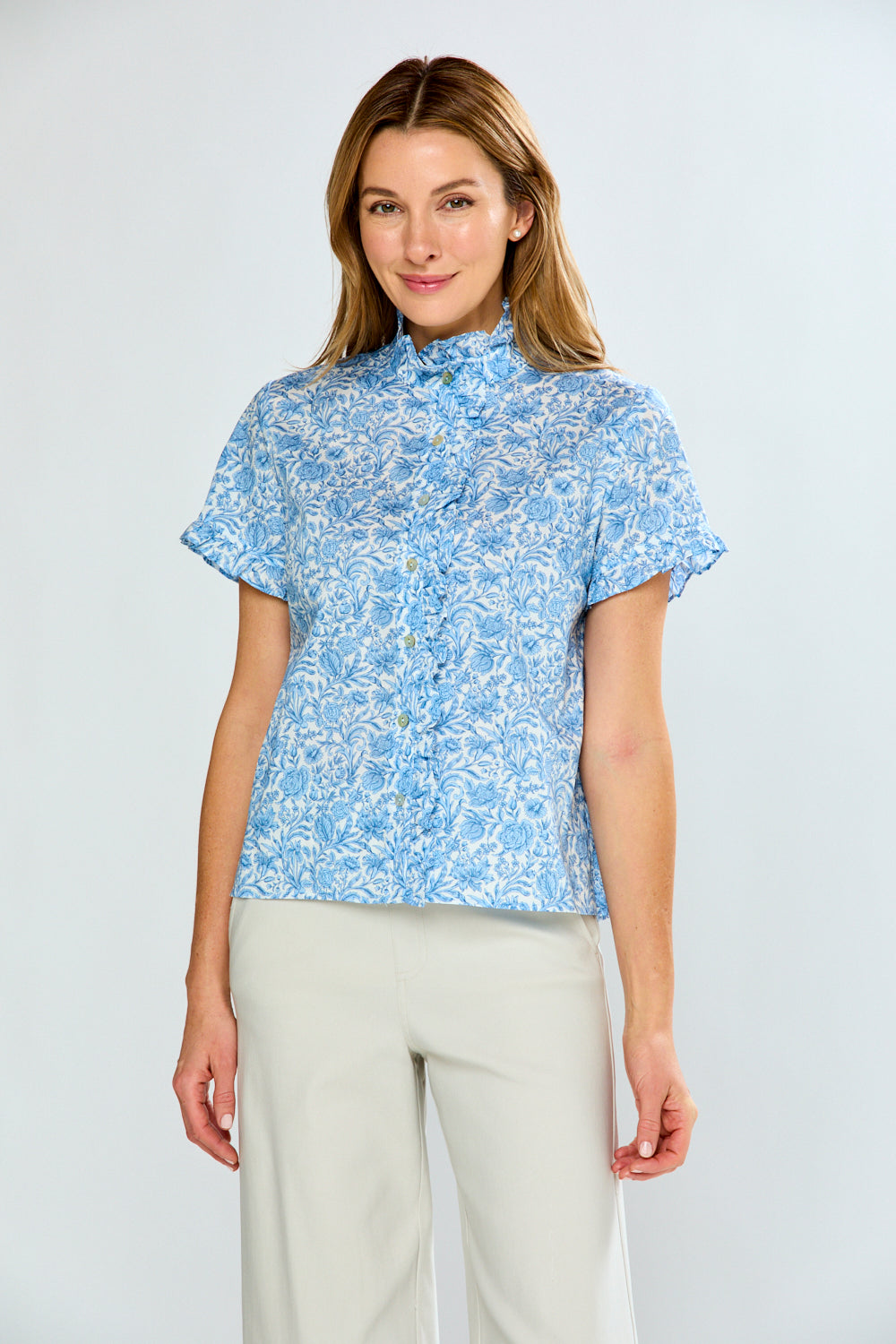 Woman wearing a blue floral blouse and beige pants on a white background