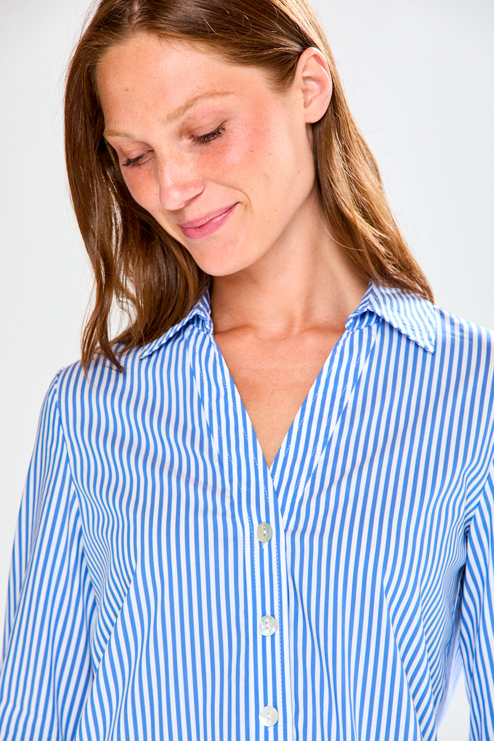Woman wearing a blue and white striped shirt against a plain background