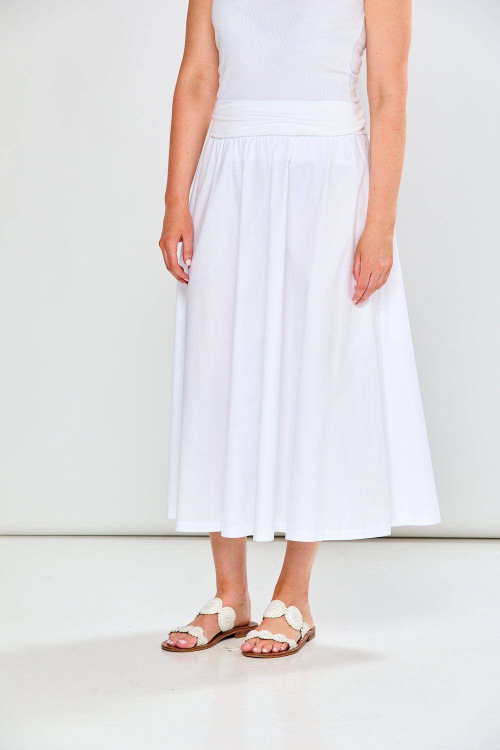 Person wearing a white dress and sandals on a plain background