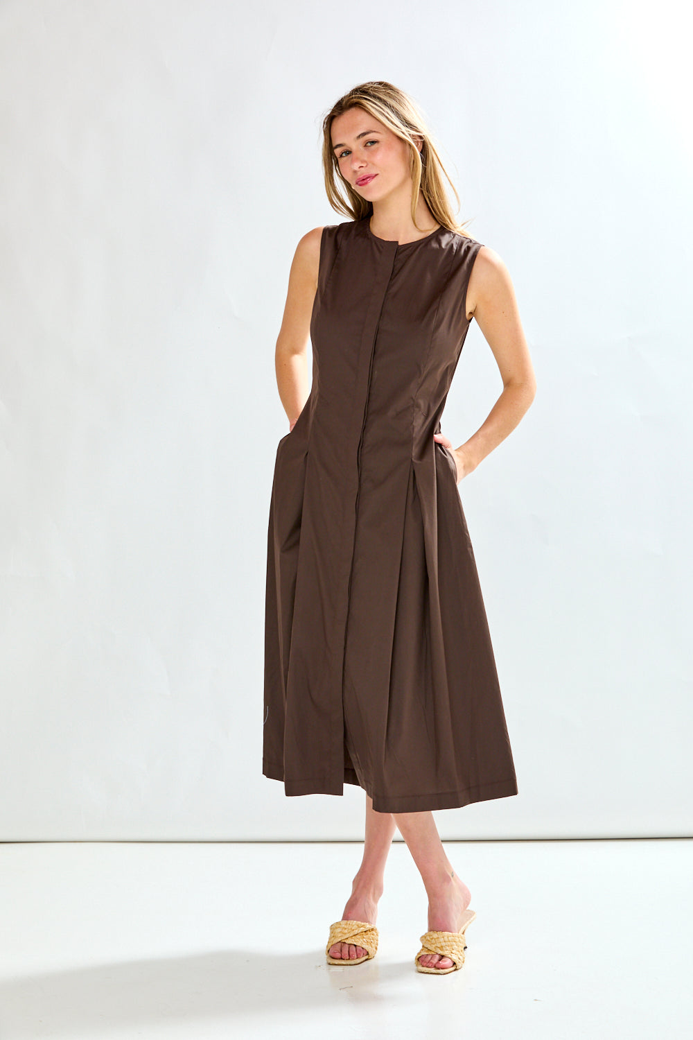 Woman wearing a brown sleeveless dress against a white background