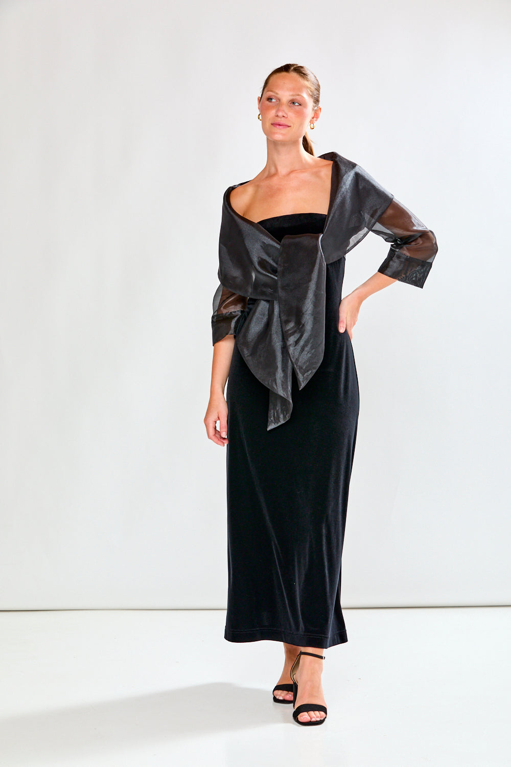 Woman wearing a black dress and black shawl against a white background