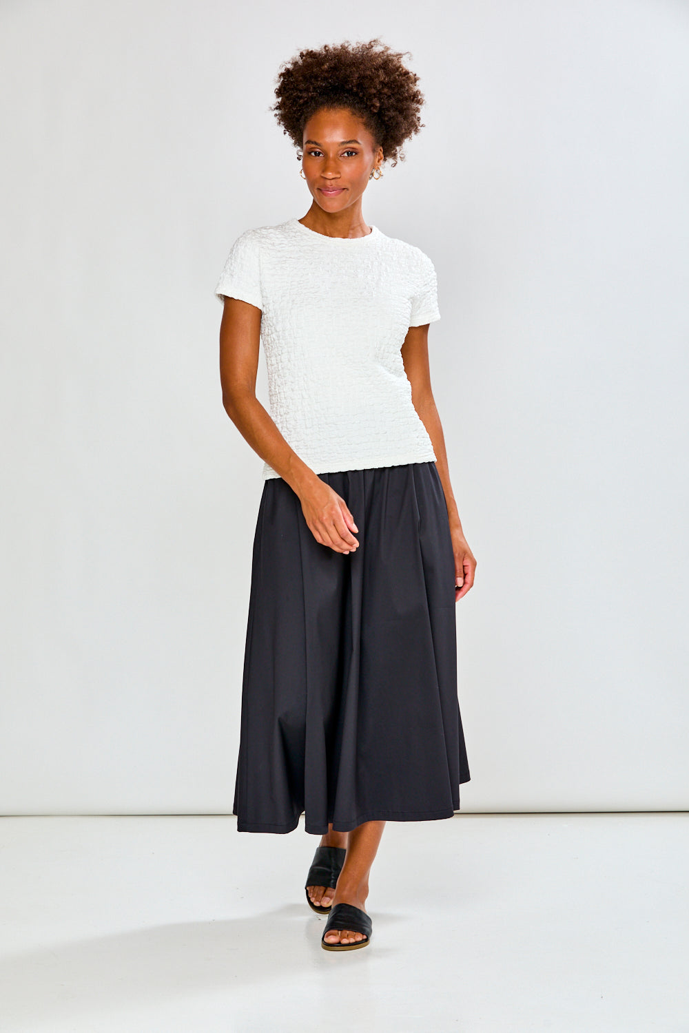 Woman wearing a white top and black skirt on a white background