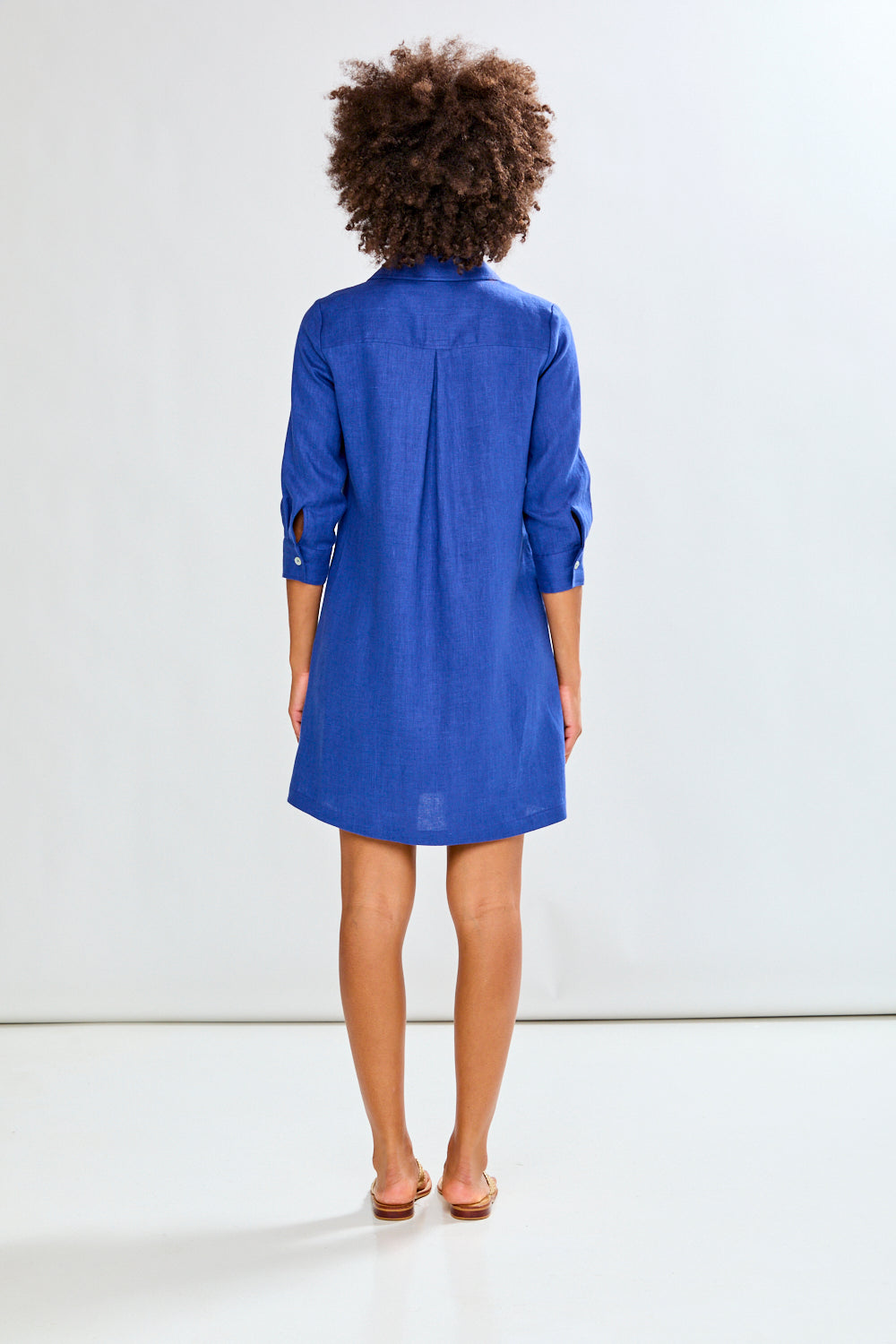 Person wearing a blue dress standing against a white background