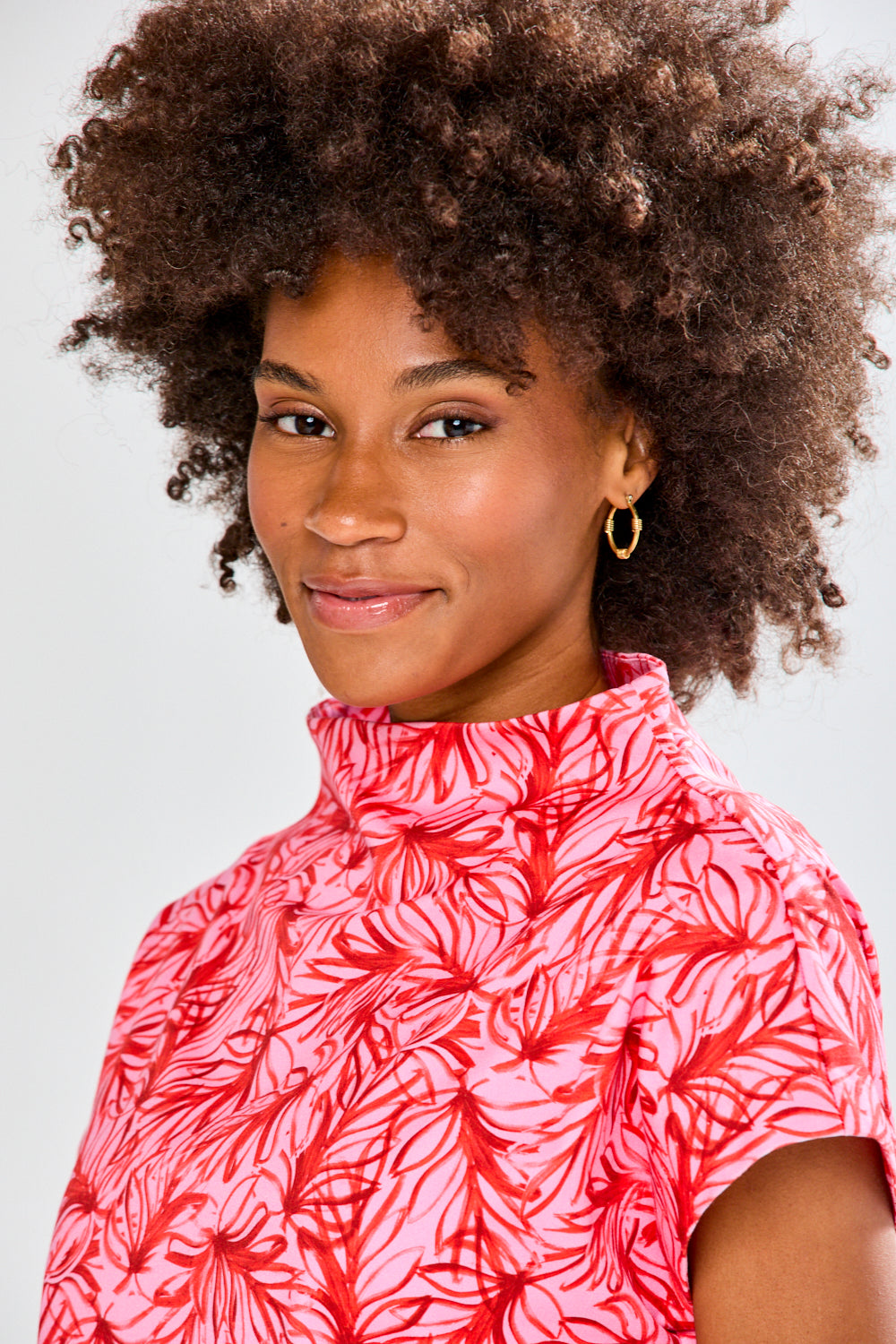 Woman wearing a pink floral patterned top against a plain background