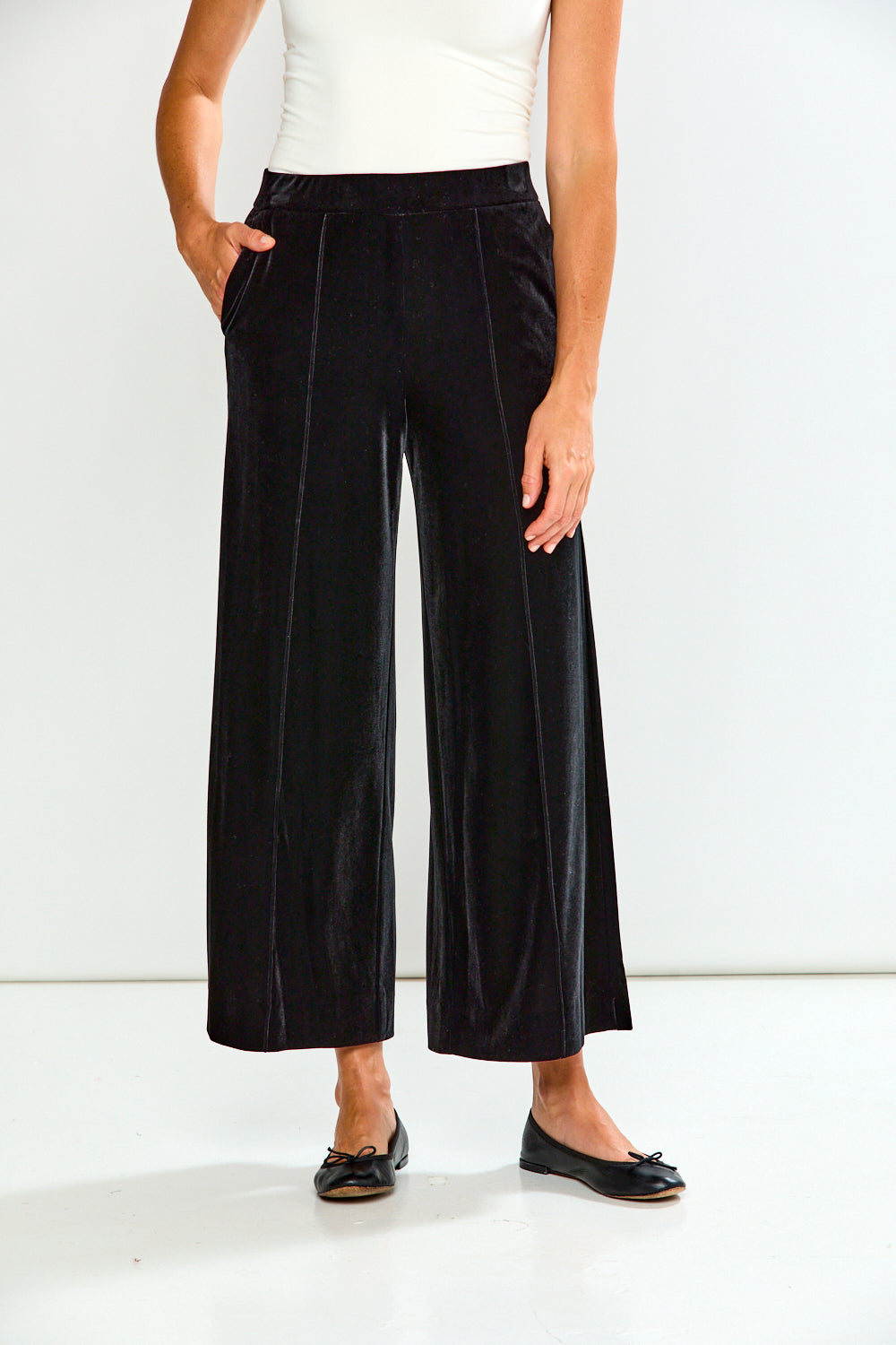 Person wearing black wide-leg pants on a white background
