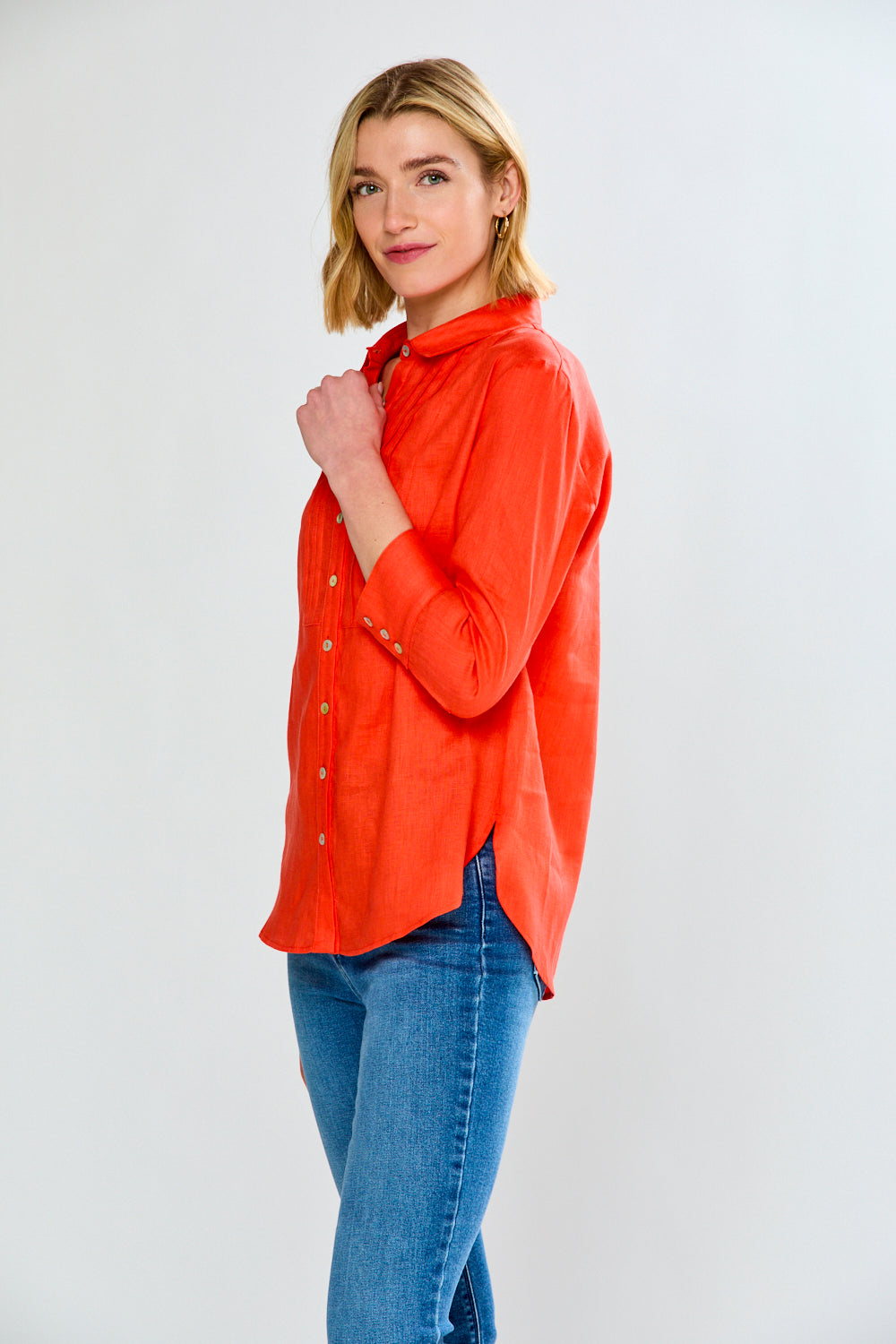 Woman wearing an orange shirt and blue jeans on a white background