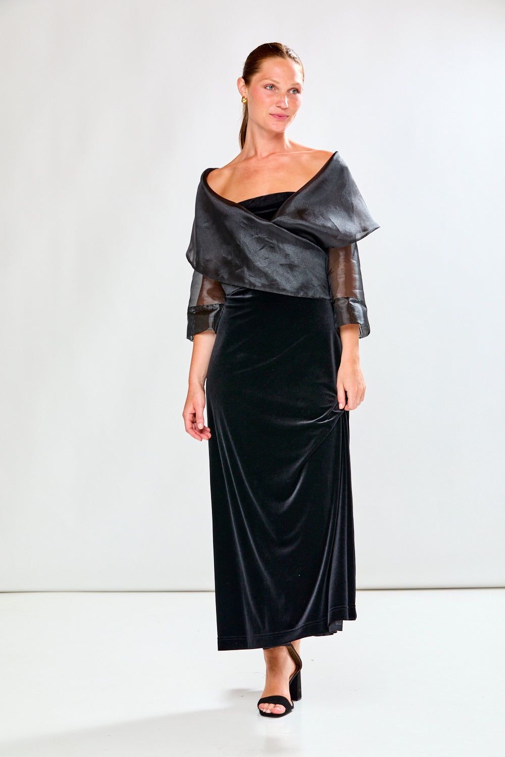 Woman wearing a black dress and black shawl against a white background