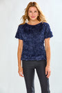 Woman wearing a textured navy blue top and black pants on a white background