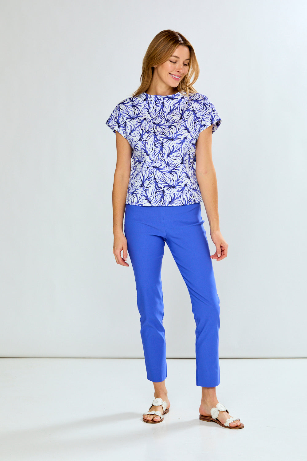Woman wearing a blue and white patterned top and blue pants on a white background