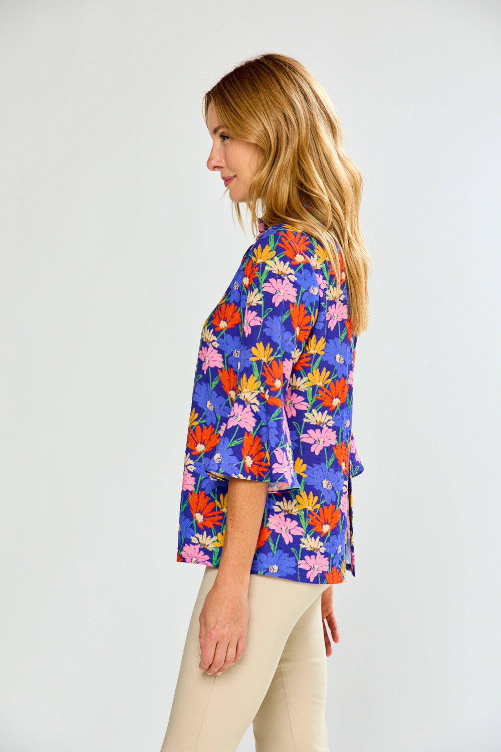 Woman wearing a colorful floral blouse against a white background