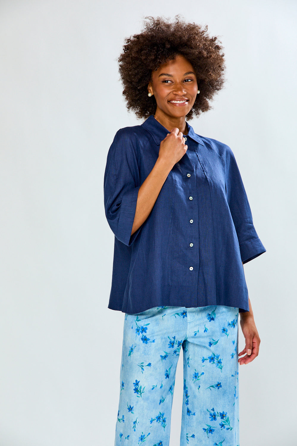 Woman wearing a blue shirt and light blue floral pants on a white background