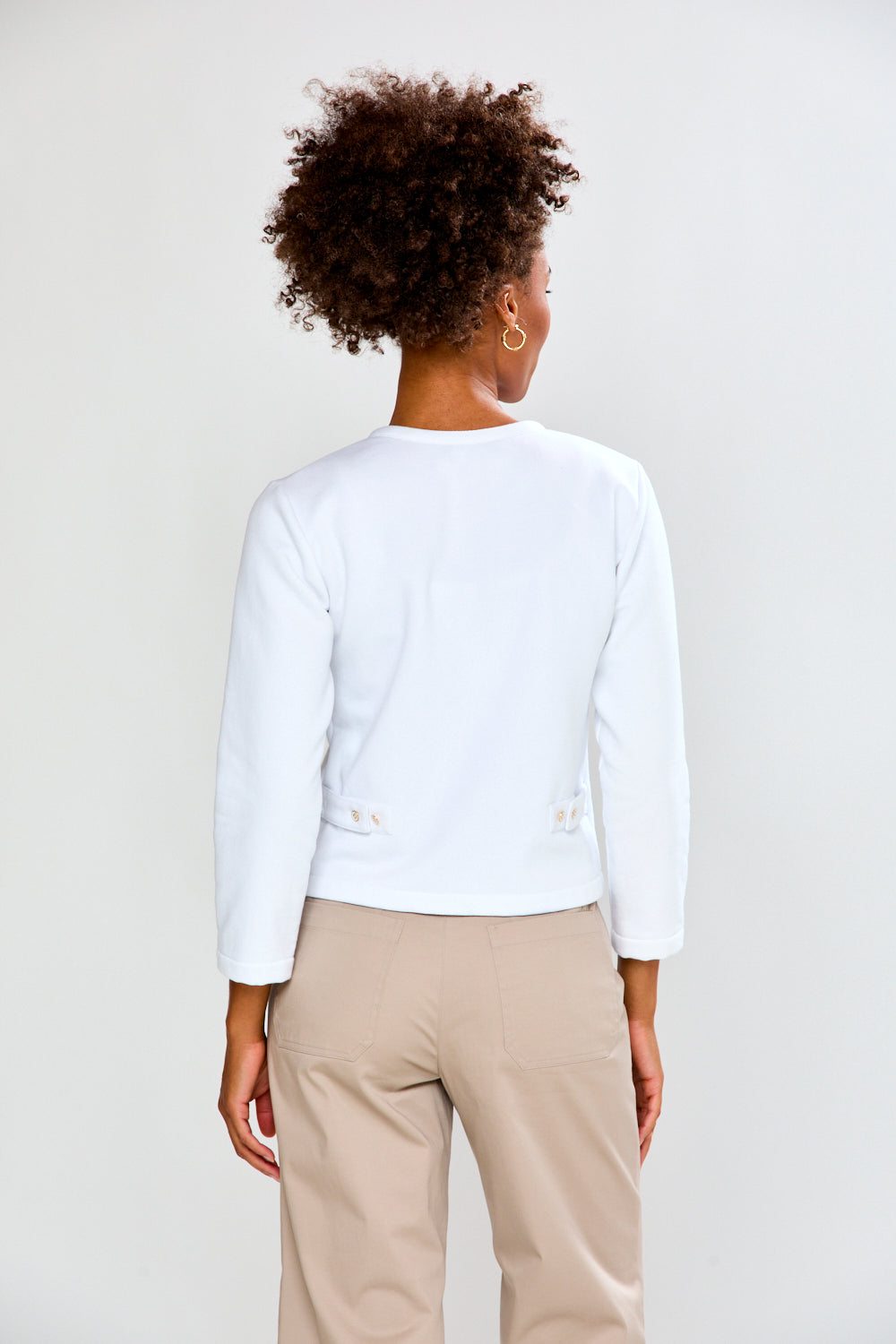 Person wearing a white blazer and beige pants on a plain background