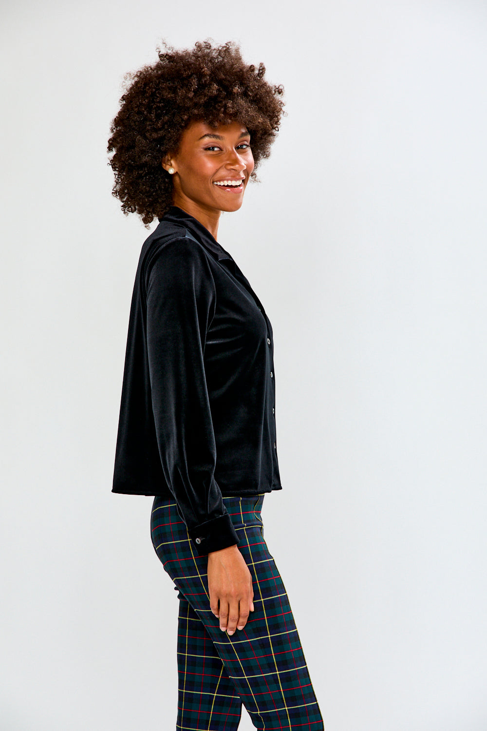 Woman wearing a black jacket and plaid pants against a white background
