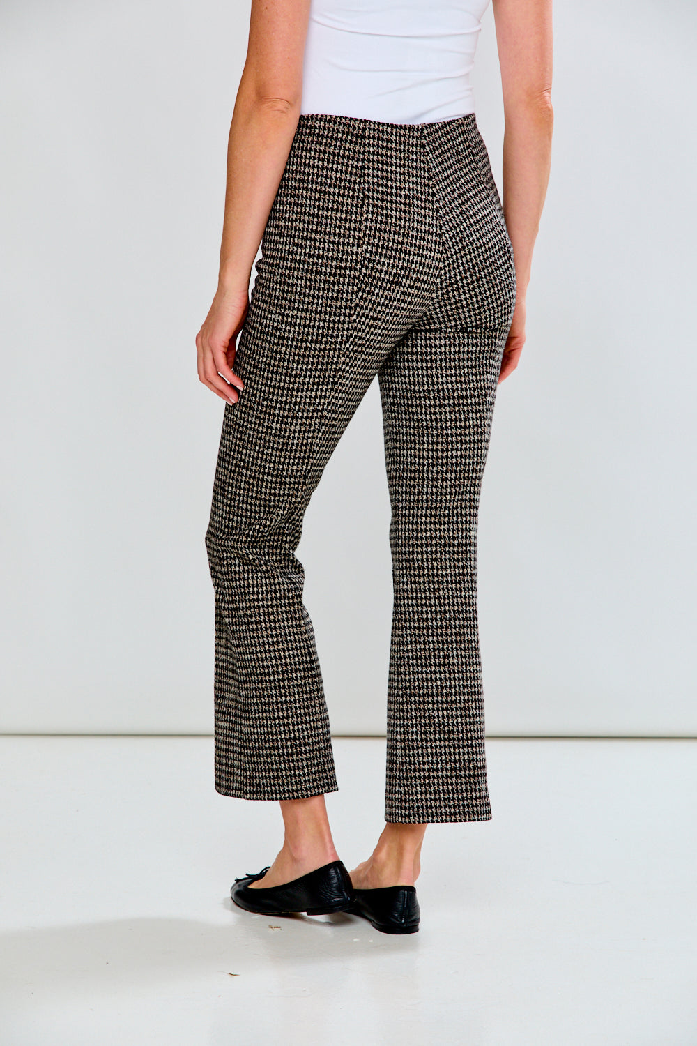 Person wearing houndstooth patterned pants on a plain background