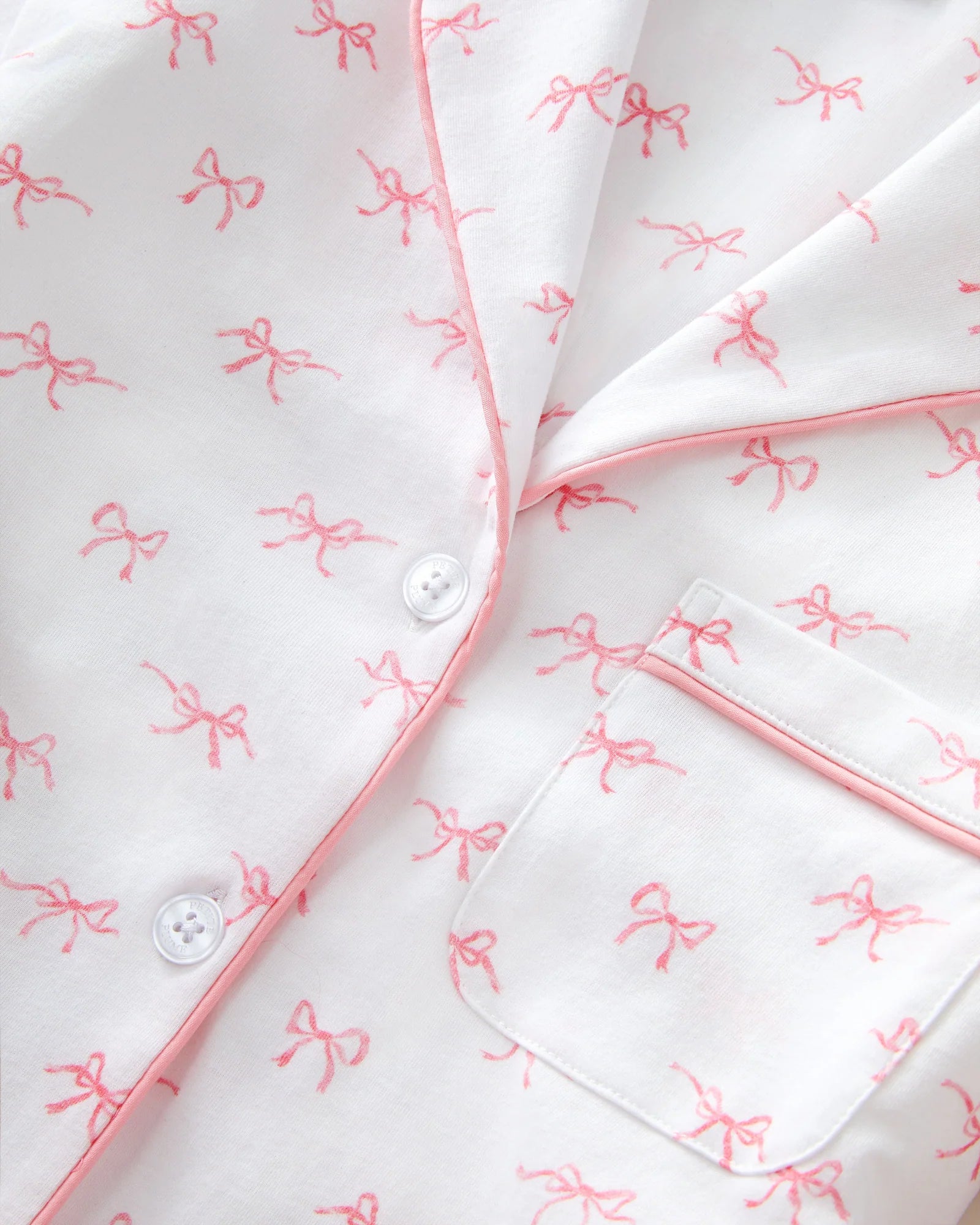 White shirt with pink bow patterns and buttons on a white background