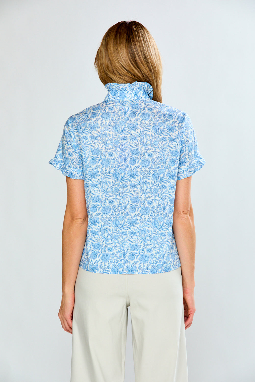 Woman wearing a light blue floral blouse against a white background