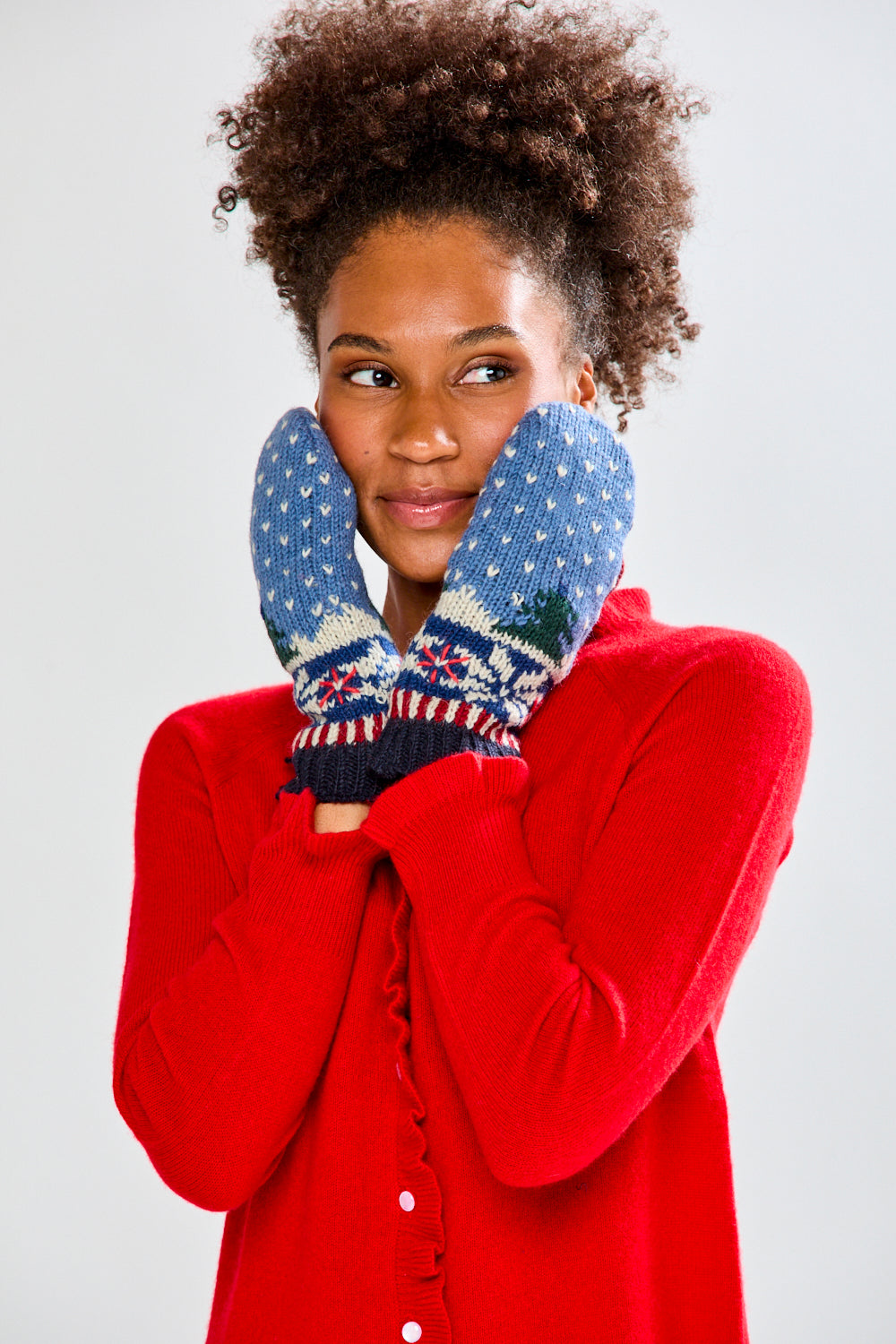 Woman wearing a red sweater and festive mittens on a plain background