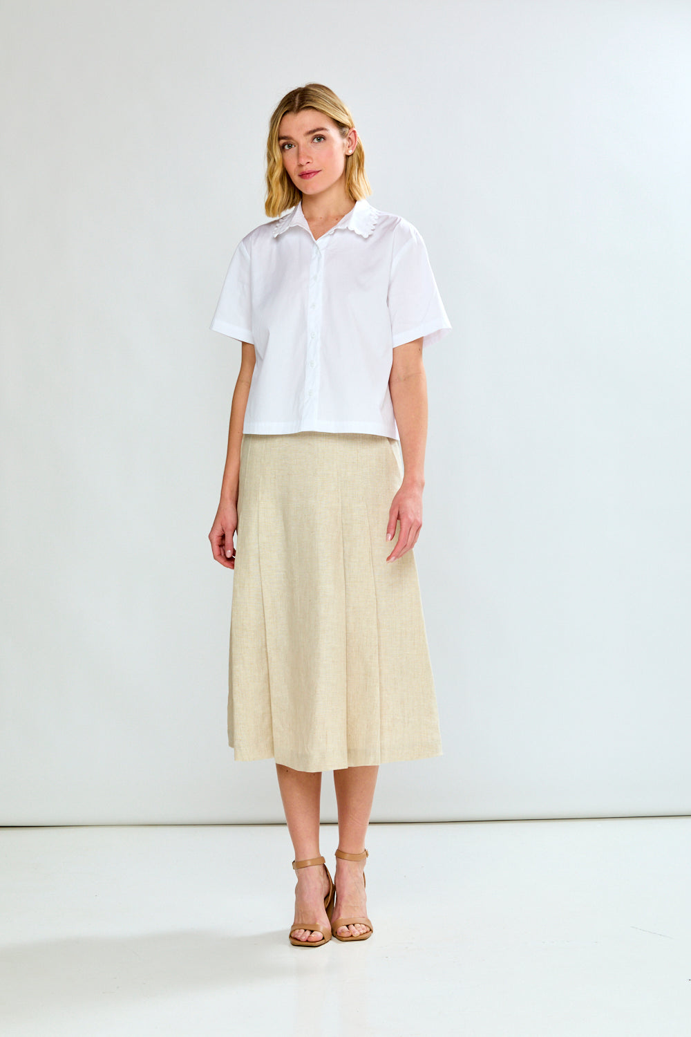 Woman wearing a white shirt and beige skirt on a white background