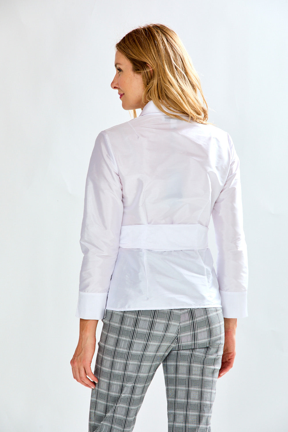 Woman wearing a white blouse and checkered pants on a white background