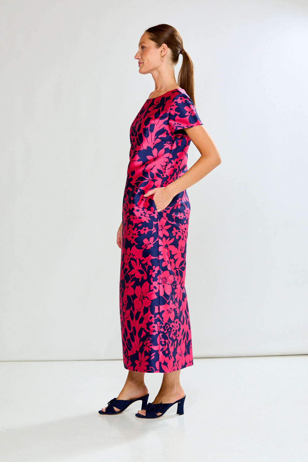 Woman wearing a pink and blue floral dress against a white background
