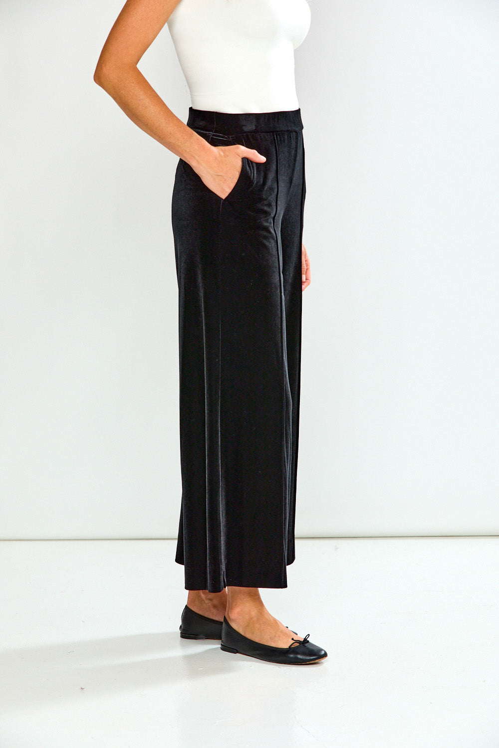 Person wearing black wide-leg pants and a white top on a white background