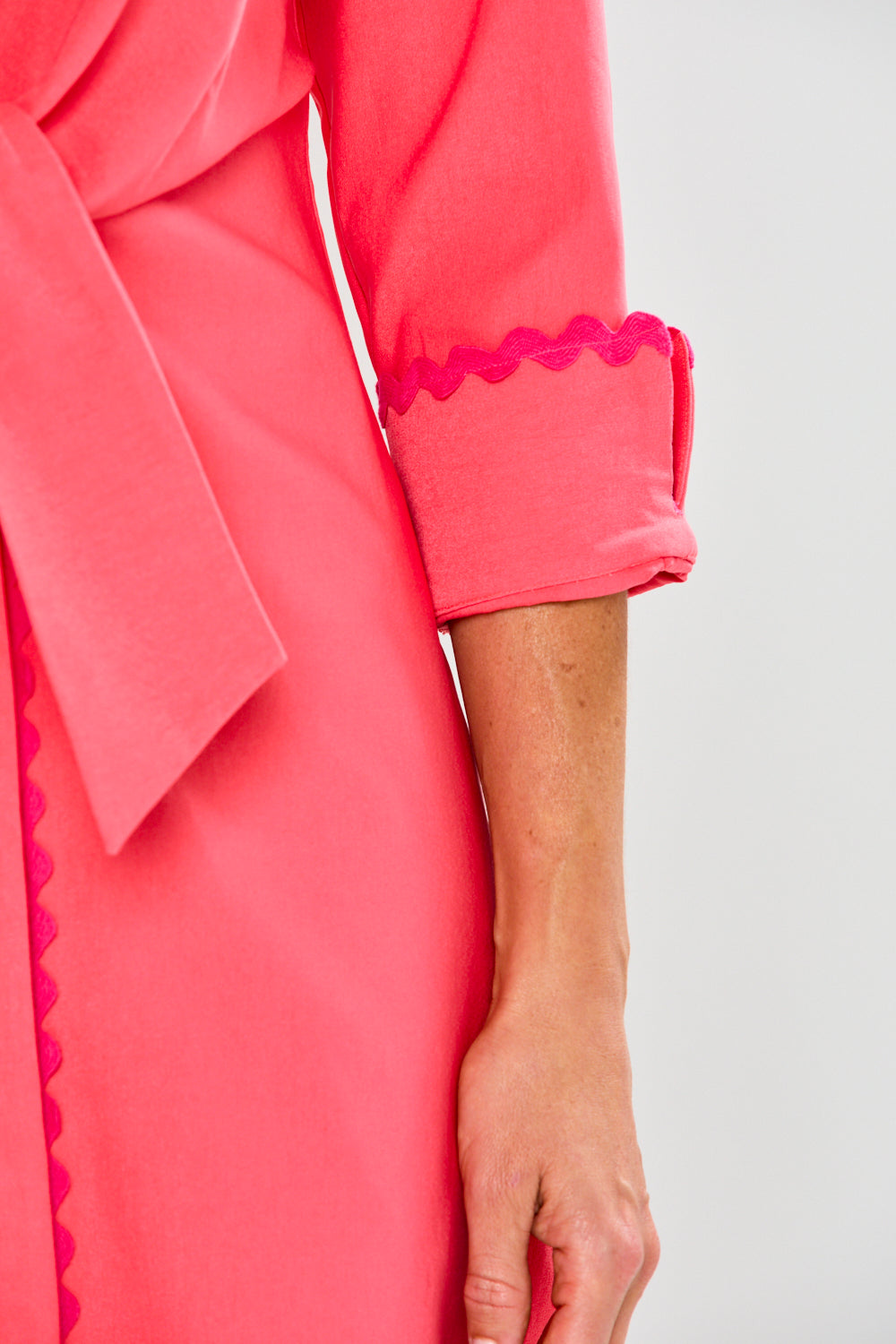 Close-up of a pink dress with ruffled details on a white background