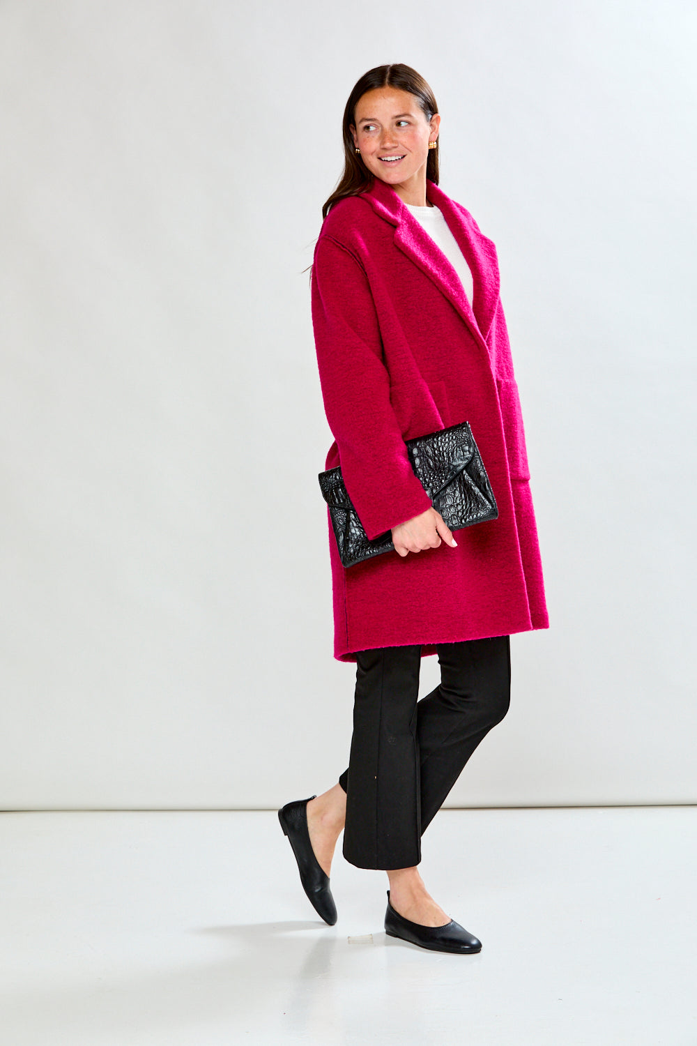 Woman wearing a bright pink coat against a white background