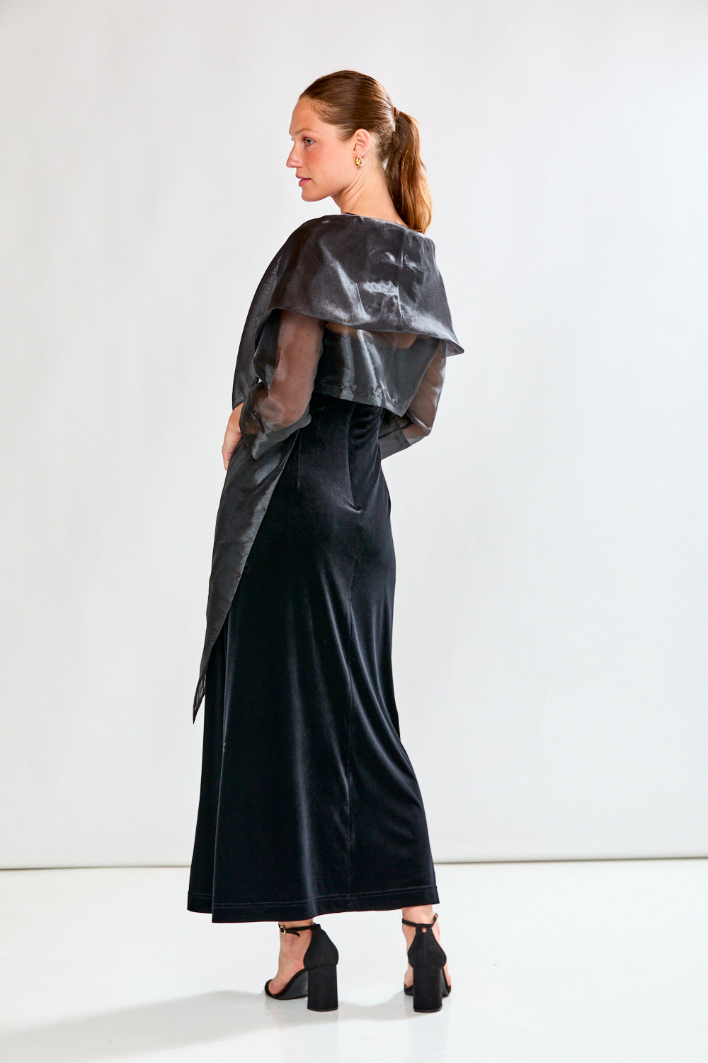 Woman wearing a black dress and black shawl against a white background