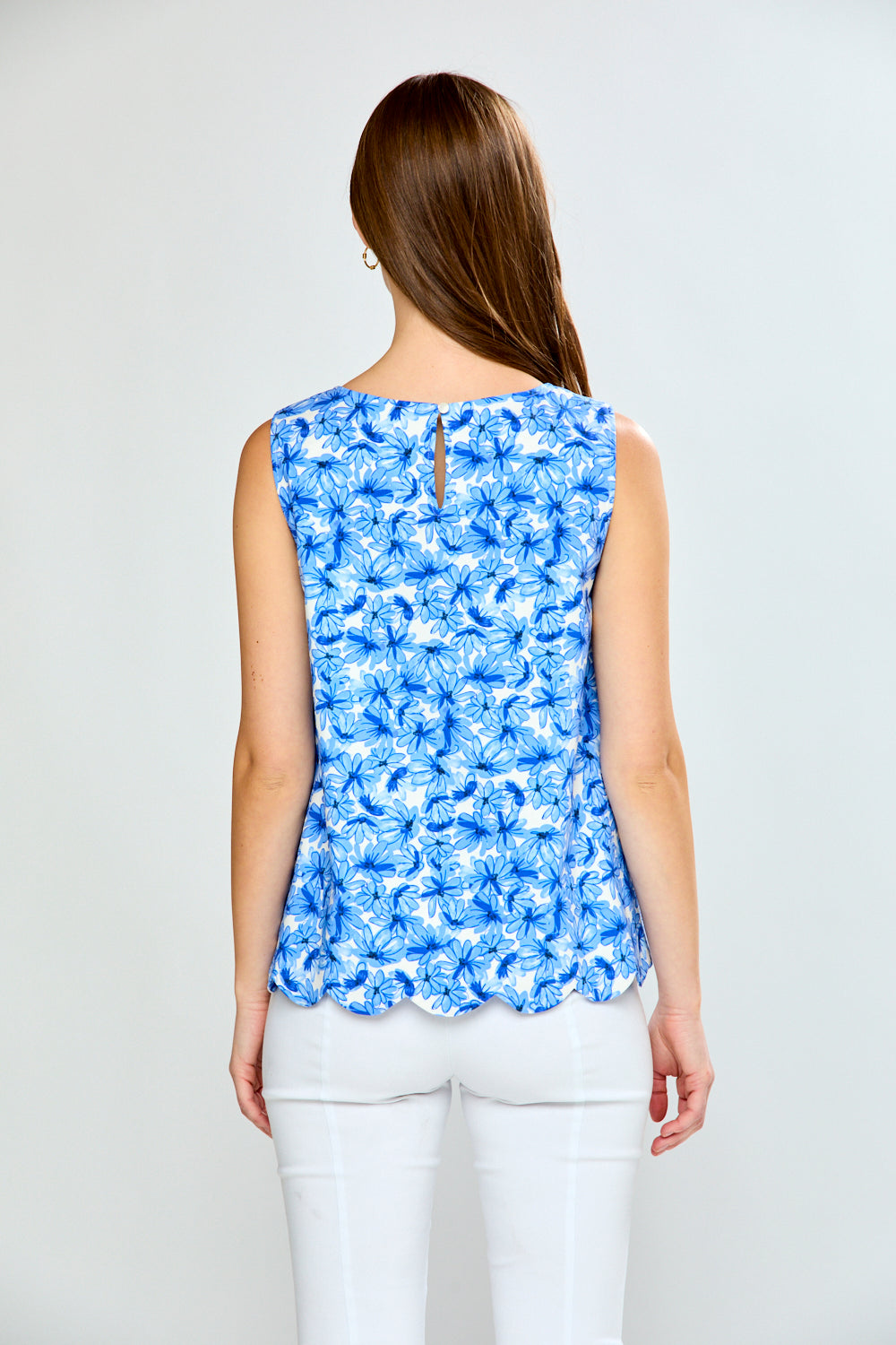 Woman wearing a blue floral sleeveless top against a white background