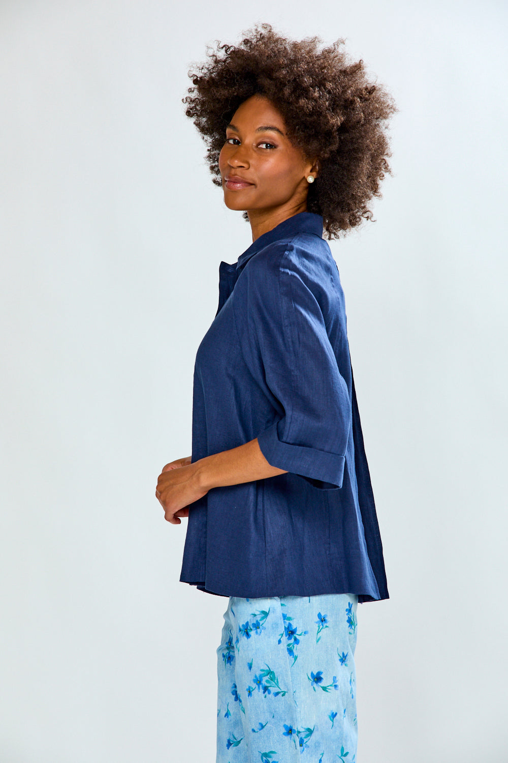Woman wearing a blue satin shirt and light blue floral pants on a white background